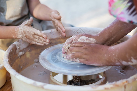 转动工作痣年轻陶匠的手在圆圈上制造一个土罐子图片