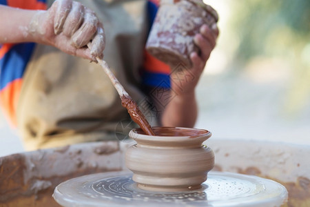 年轻陶匠的手在圆圈上制造一个土罐子手指工艺接触图片