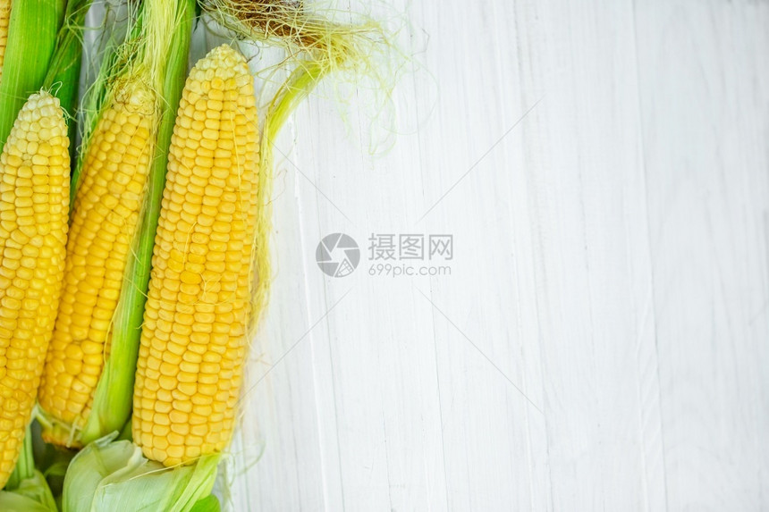 在一个生锈的花园里产玉米在白色木制乡村桌边的一个白木板上浅深的焦点农业的概念在一个生锈的花园里产玉米成熟植物黄色的图片