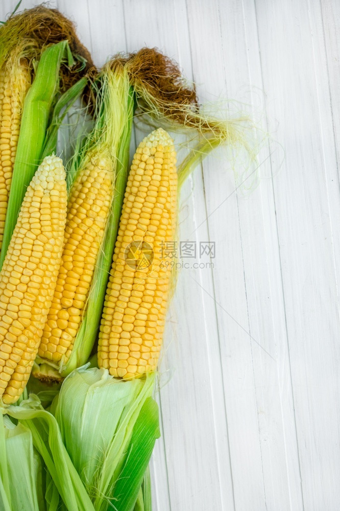 浅的成熟目在一个生锈花园里产玉米在白色木制乡村桌边的一个白木板上浅深的焦点农业的概念在一个生锈的花园里产玉米图片
