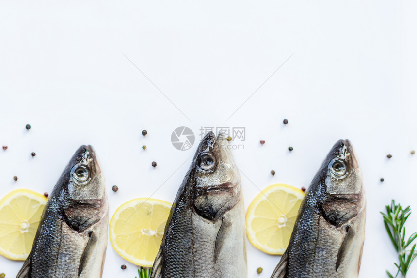 盐水白色石板桌上放着香料和草的生鲈鱼带复制空间的顶视图新鲜鲈鱼白色石板桌上放着香料和草的生鲈鱼调味料地中海图片