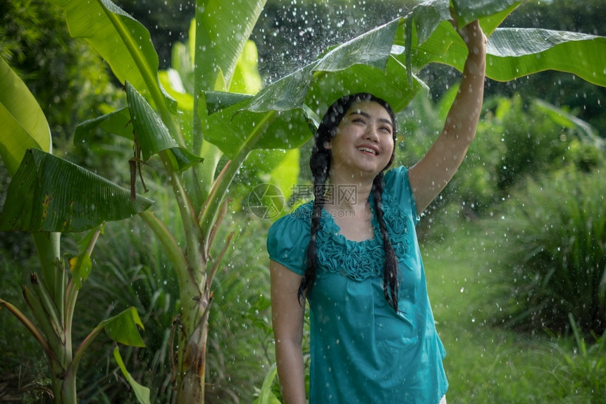农场在绿花园背景下雨时一位年轻亚洲女身着香蕉叶的黑头发肖像年轻的快乐图片