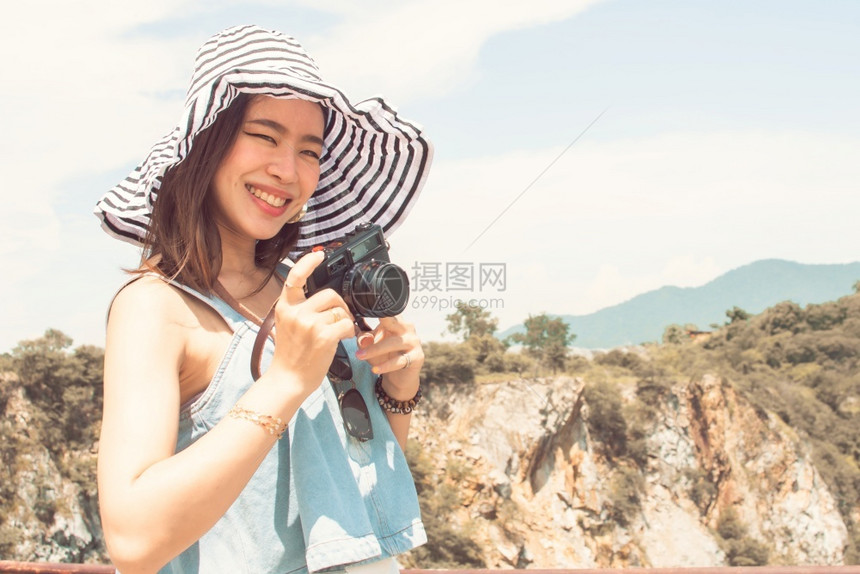 亚洲美丽的女在暑假旅行时微笑并拍照山地和蓝天空背景模糊夏天旅行时笑着与拍照女自然亚洲人图片