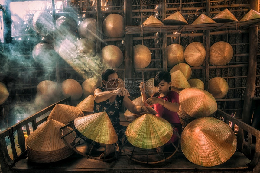 东方的旅行手工制作越南老匠在霍希明市ApThoiPhuoc村的老旧传统房屋中教孙辈制作传统的Vietnam帽子传统艺术家概念图片