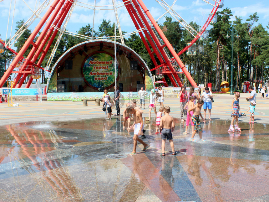 儿童与父母一起在游乐场玩戏夏日在哈尔科夫高基公园喷泉儿童在城市喷泉里玩水游戏儿童在运动场和热暑喷泉玩他们的步行欢乐图片