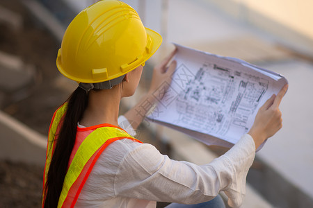 解释妇女工程设计硬帽安全西装持有建筑施工蓝图检查作妇女企业主难的就图片
