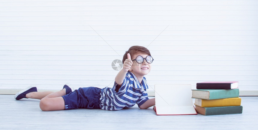 那里快乐的教育一个书呆子的班纳带着眼镜的天主教小男孩正在读书做一个拇指上面有一个复制空间图片