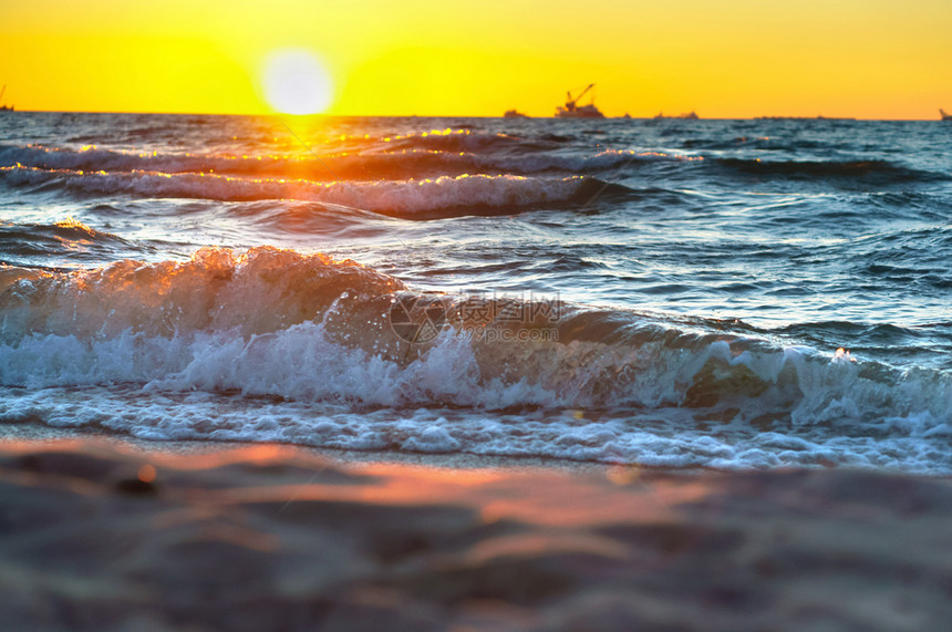 黄色的云在波罗海浪冲和辉煌日出时海边的红黄夕阳天气图片