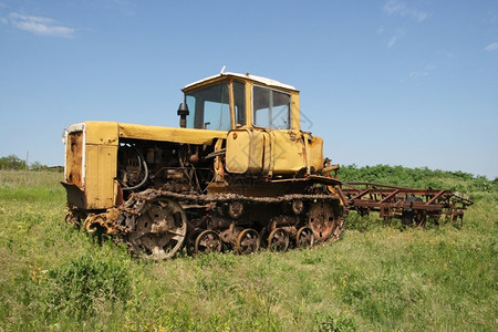 黄色的耕地行业绿草和天空背景的旧黄色拖拉机DT75苏联1963年图片