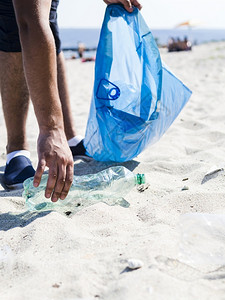 男子收拾沙滩上的塑料瓶图片