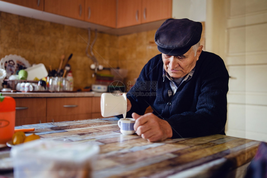 身着黑色毛衣和帽子的老年养恤金领取者农民穿着黑色毛衣和帽子坐在家桌边喝咖啡或茶独自坐在家里倒锅的咖啡白种人木制的年长图片