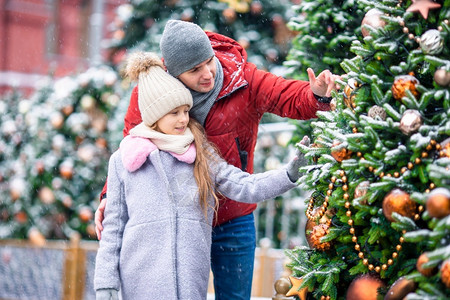 幸福父亲一家和可爱的小女孩在雪地里的冷杉树附近过新年坦率常绿图片