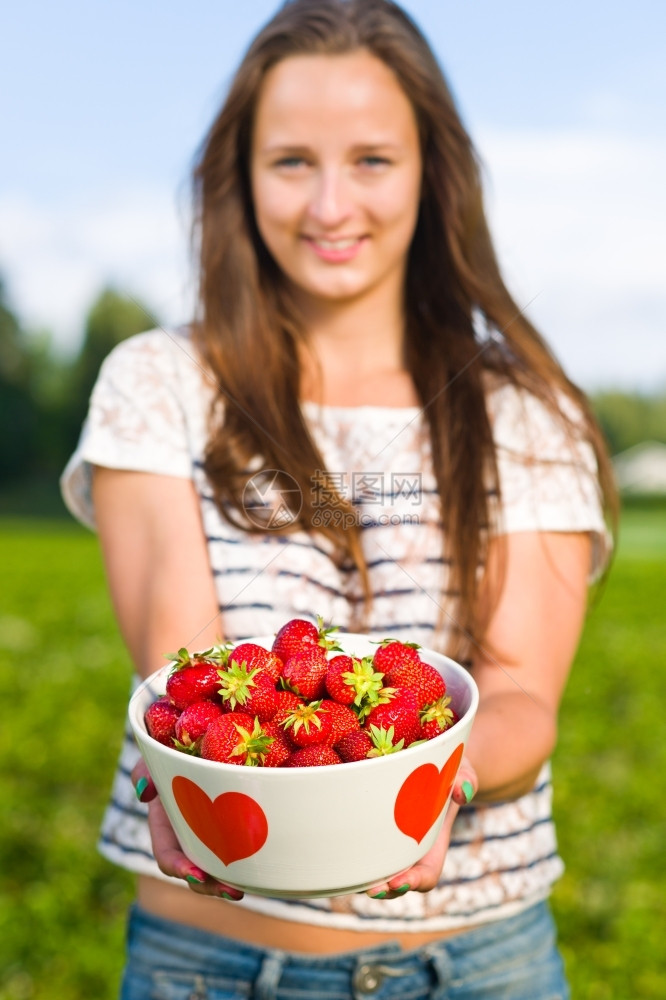 丰富浆果农民美女孩拿着一碗新鲜草莓专心吃碗图片