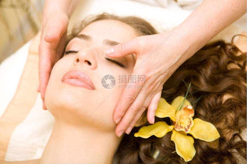 关心健康又的SPA年轻又漂亮放松的女人做面部按摩兰花长棕色头发温泉身体图片