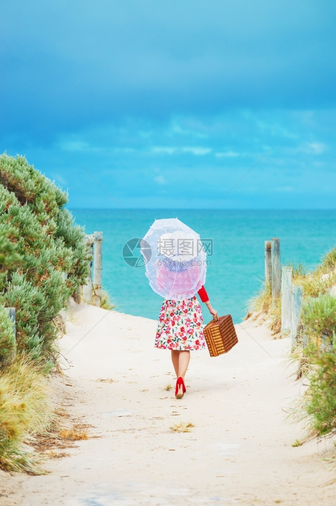 闲暇热的在海滩上穿旧式礼服的漂亮女旅行者当地专注女松弛图片