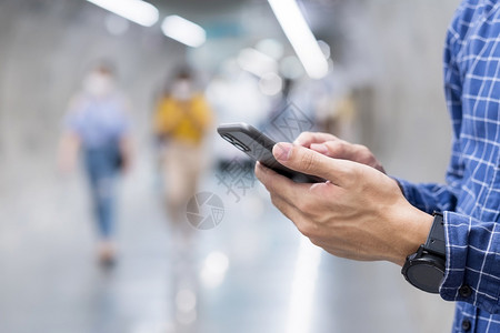 地铁新开新的保护疾病持有和使用智能手机发送短信的青年临时商务员在地铁业中打触摸屏幕手机的旅游男子生活方式技术和社交媒体网络概念手持和使用背景