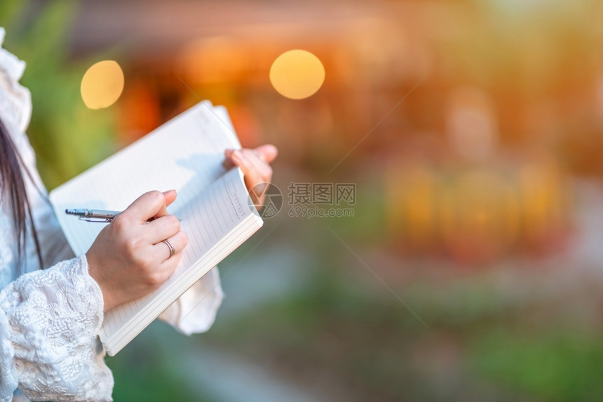 商业妇女站在咖啡店商业生活方式笔记本上写的女商人站着在业生活风格中作笔记学生成功的书面图片