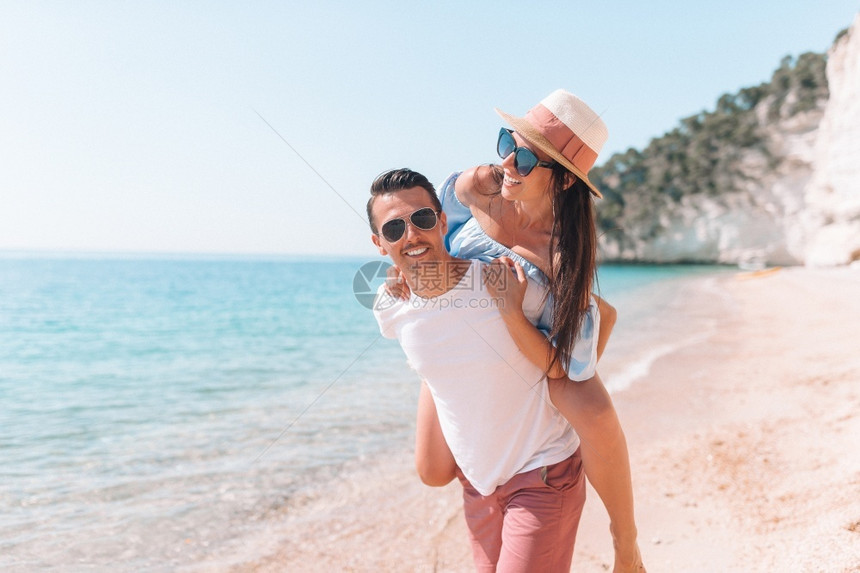 欢乐家庭享受蜜月在海边的相片上快乐情侣在海滩上太阳镜里过着快乐的一对喜悦男朋友迷人的图片