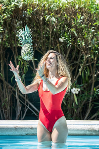 空气水果穿红色泳衣的女人把菠萝扔进游泳池里请享用图片