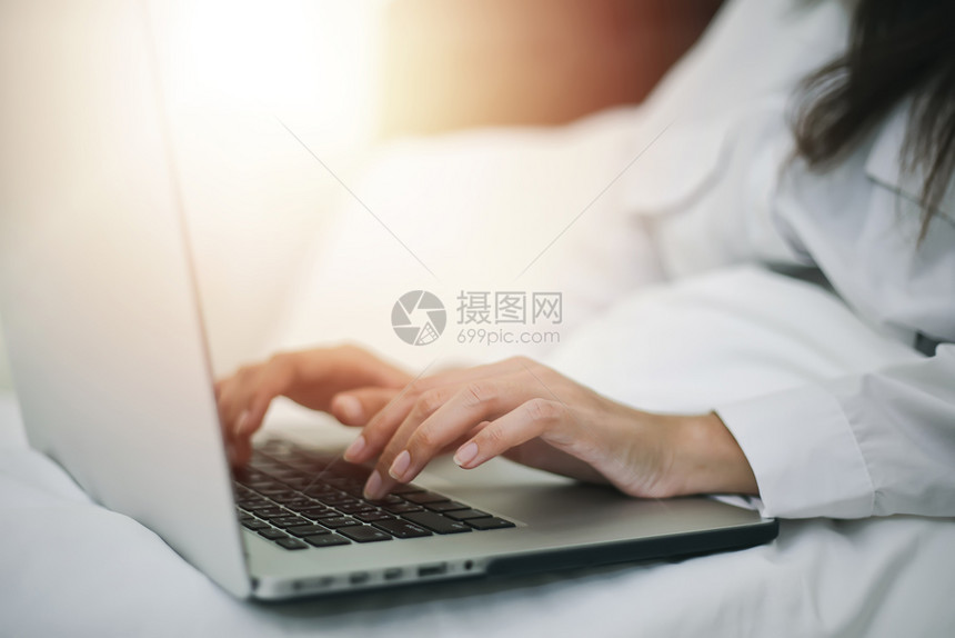 屋亚裔妇女用笔记本在床上工作她笑着享受在家工作现代的互联网图片