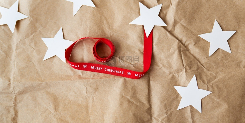横幅一条红丝带上面写着圣诞快乐和手套一只红色袜子铺在牛皮纸上圣诞节庆祝概念12月5日横幅一条红丝带只色袜子铺在牛皮纸上圣诞节庆祝图片