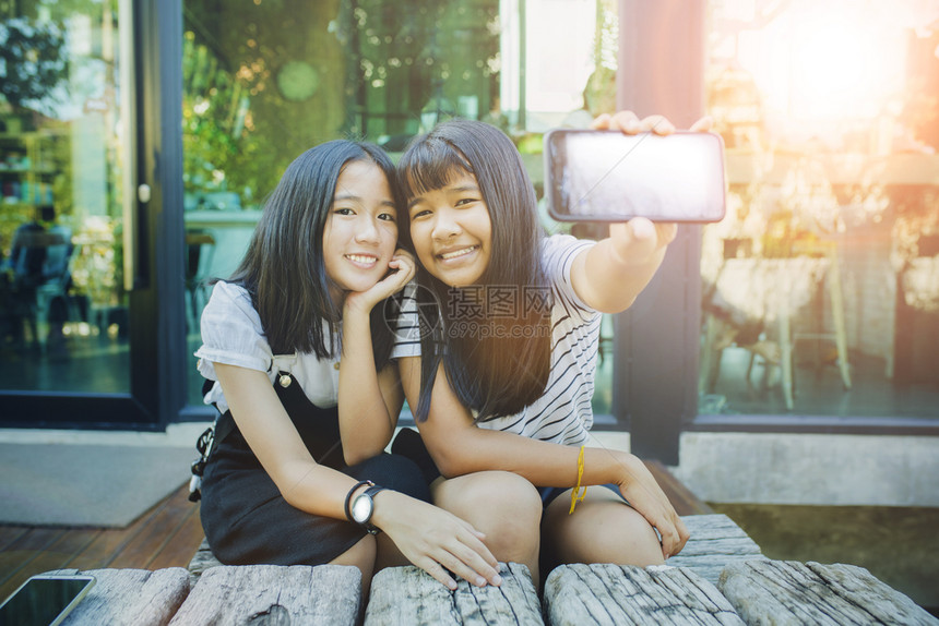 简单的使满意两个亚洲青少年展示了智能电话屏幕的白色和牙齿笑脸微的快乐情绪Name社会的图片