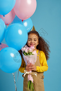 粉色蓝色气球肖像可爱的小女孩在帽子中拿着一束多彩气球花束蓝背景漂亮女孩得到了一个惊喜事件或生日派对庆祝小女孩拿着气球和花束小女孩拿着气球和花背景