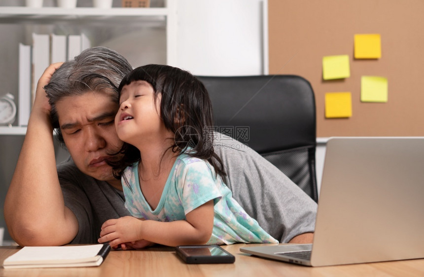 现代的亚洲父亲试图在家庭办公室用笔记本电脑与一个陷入混乱的女儿一起工作在隔离期间新式的生活方正常留在家中的概念自由职业和父亲概念图片