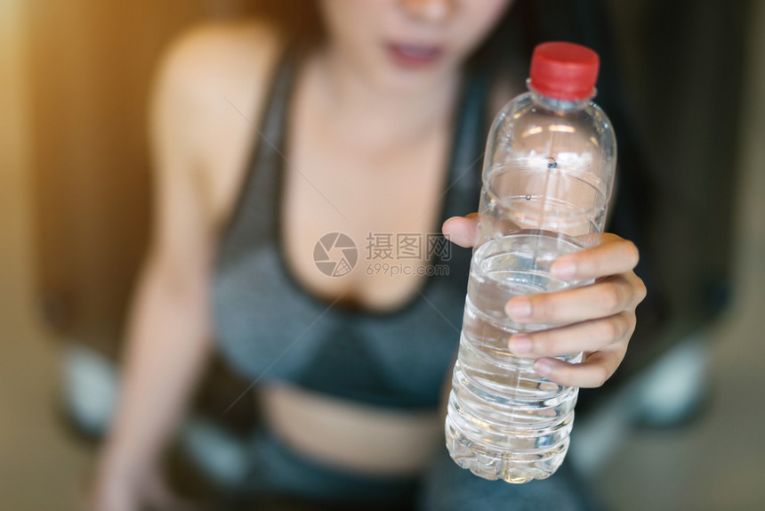参加锻炼训练的亚洲妇女在体育健身室内和俱乐部中用运动设备打一瓶水并配有健身器材她们从事锻练训体操背景福利内部的微笑图片