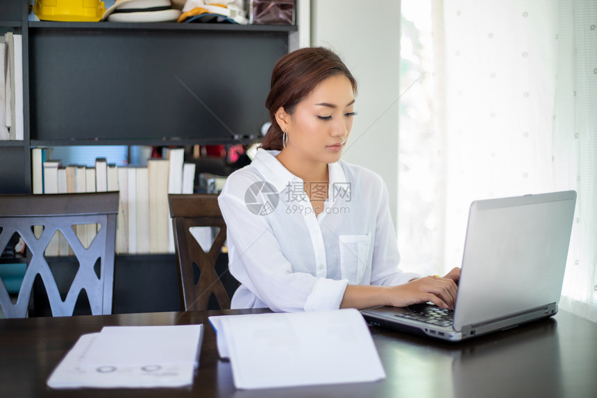 女快乐的亚洲美丽商业妇女检查文件并使用笔记本在家中工作以达到社会距离和自我责任概念亚洲美丽的商业女人笔记本电脑图片