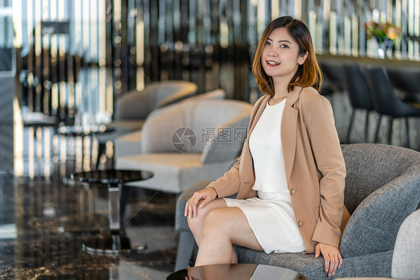 身着正式西装坐在现代大厅办公室或合用空间沙发上咖啡休息时间工作之后的尚和生活方式企业人士概念中的亚洲女商人在现代大厅办公室或共同图片