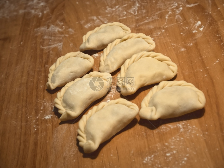 6个未煮熟的面包加卷心菜有传统的卷式面团饼躺在准备的木制厨房餐板上在煮饭前做好烹饪准备好的自制有图案图片