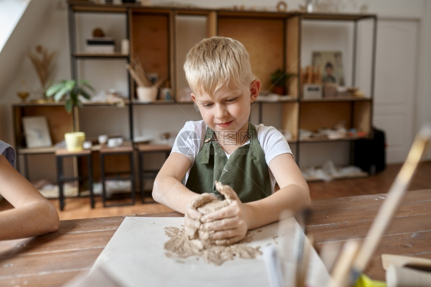 手工oopicapi雕塑家小男孩用粘土工作在坊里的孩子在艺术学校上课民间工艺的年轻大师愉快的爱好乐童年小男孩用粘土工作在坊里的孩图片