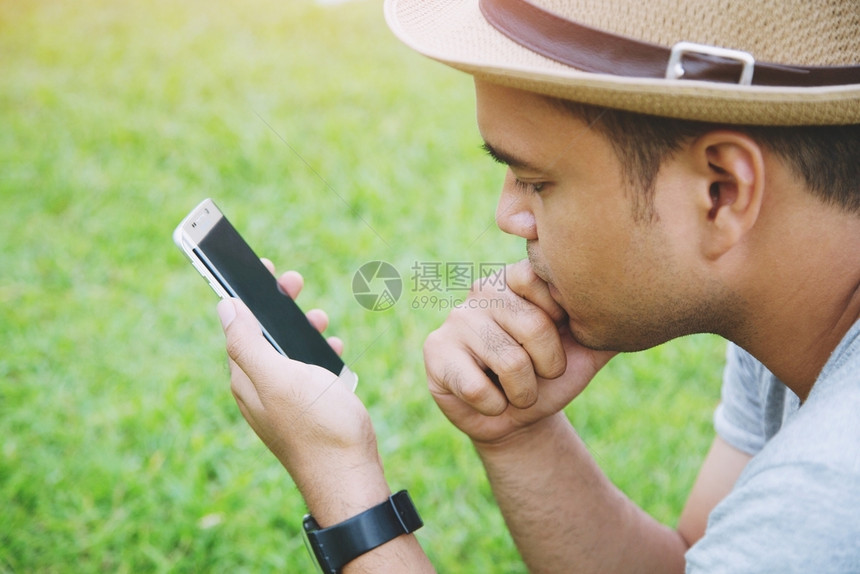 印度尼西亚青年男子戴帽坐在使用手机智能电话的座位上屏幕阿拉伯图片