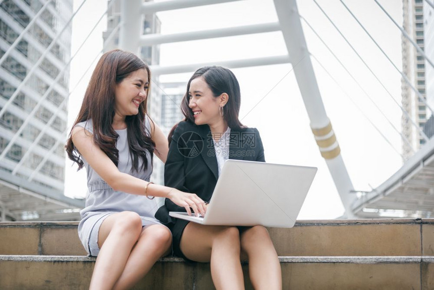 商界女专业的社会两名从事膝上型计算机工作的女商人她们拥有快乐的趣情感激动式笔记本电脑商业办公室雇员技术协作企业工团队合作会议营销图片