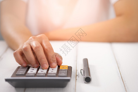成本使用桌上计算器的女商人选择焦点在光线上钱账单背景图片