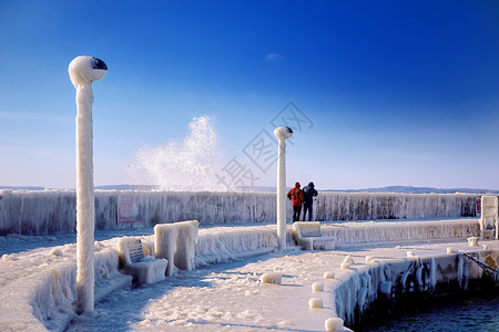 寒冷的灯塔和码头在暴风寒冬日天水白色的图片
