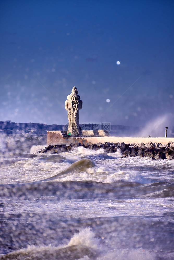 寒冷的灯塔和码头在暴风寒冬日蓝色的天戏剧图片