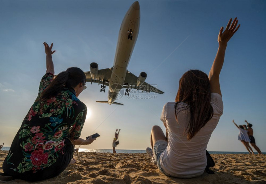 两名旅行女子的场景展示手和滑稽与飞机搭乘在泰国普吉际机场附近的海滨距离降落泰有趣的自然海洋图片