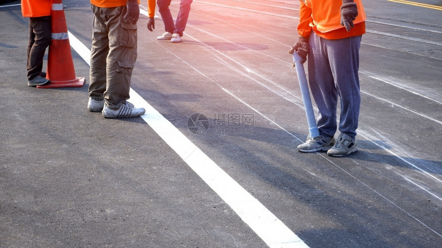 运动鞋在职的公路工人小组低正致力于在沥青公路上为油画交通彩色线打标识有选择地重点关注该城市街道表面的铁轨交叉点维护图片