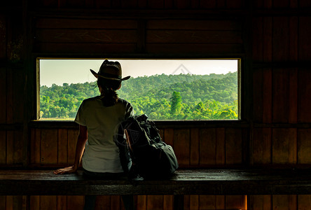 草地缺席的公园年轻亚洲妇女戴着帽子坐在木板凳上晚野生物观察塔上看热带森林的美丽景象阳光变暖后独自旅行的概念是女单独旅行图片