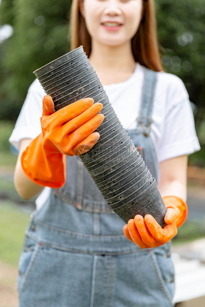 周末女园艺人关于堆叠塑料罐子的构想数量由女绿衣管理者掌握准备填满土壤和种子草地外部的图片