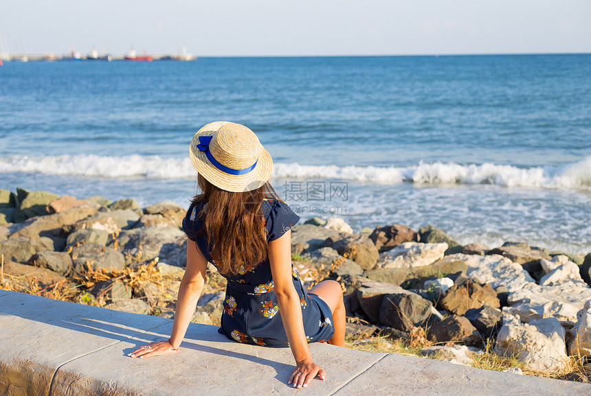 女冷静的戴着帽子漂亮女孩坐在海边石块上戴着帽子的漂亮女孩坐在海边思考图片