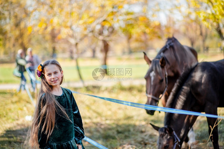 童年快乐女孩骑马站在棚的栅栏附近一个孩子坐在马背上野和花头女孩在腰上手推站在棚的围栏旁边友谊母马图片