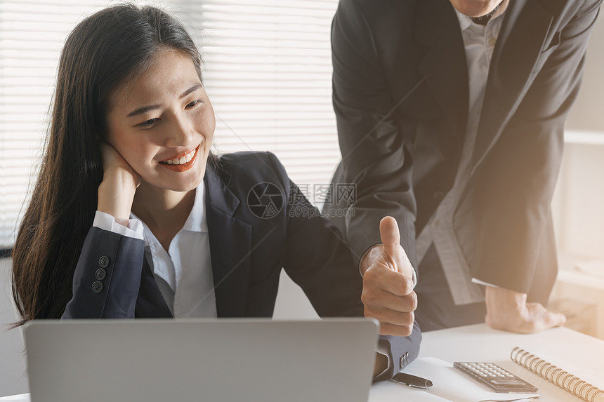 财产老板男雇主敬佩年轻的亚洲女秘书她的成功和好亚洲商业女坐在办公室里微笑的面容上露出大拇指纸工作图片