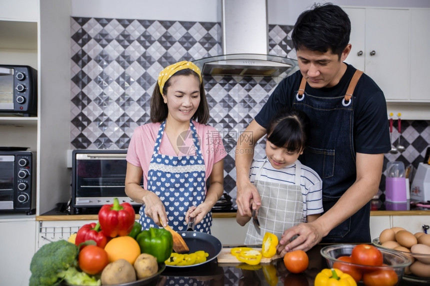 年轻的亚洲家庭正在做饭父母女儿家里厨房做饭节假日的家庭活动和娱乐快概念是家庭活动在娱乐中欢的理念爱童年图片