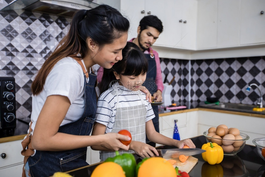 他们的爸吃亚洲家庭正在做饭父母女儿家里厨房做饭节假日的家庭活动和娱乐快概念是家庭活动在娱乐中欢的理念图片