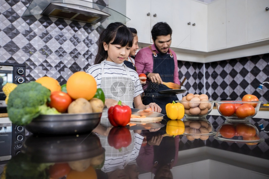 吃亚洲家庭正在做饭父母女儿家里厨房做饭节假日的家庭活动和娱乐快概念是家庭活动在娱乐中欢的理念桌子年轻图片