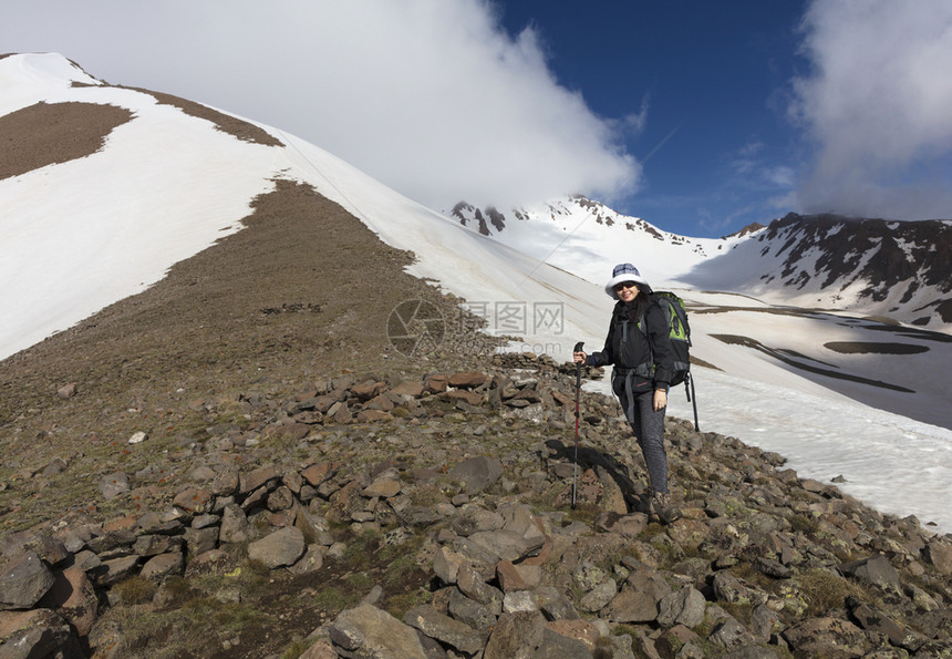 戳一位背着着一个的旅游妇女手里拿着一个追踪棒前往雪地高山进行一场运动游客从山上爬到雪地顶峰探索女孩图片