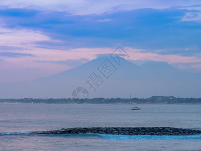 旅游海滩将太阳与远处看到的火山同在库塔Kuta夏天图片